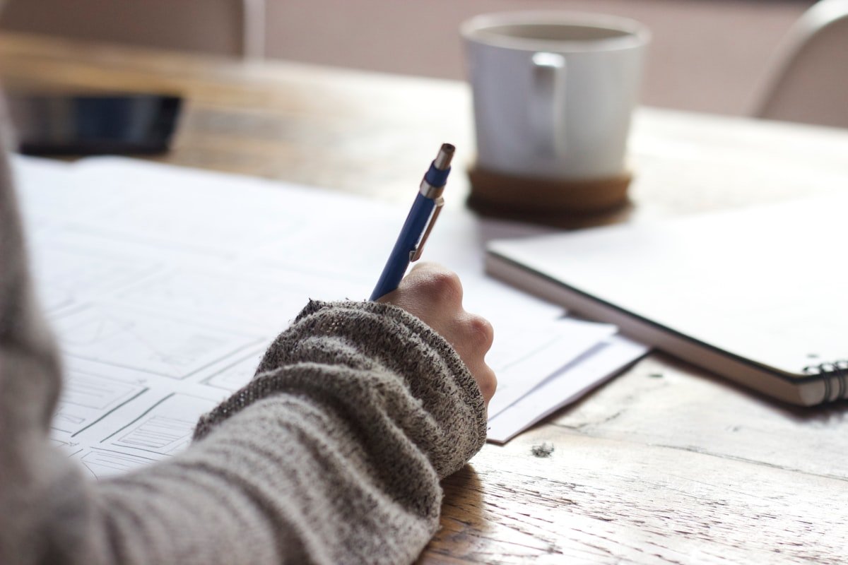 A person writing notes at a wooden desk